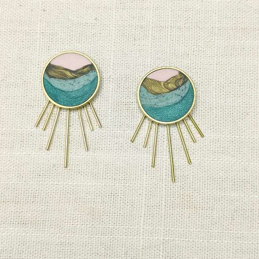 A circular earring set with spokes simulating sun rays coming from the bottom of the circle. The inside includes layers of pink, gold, mint green, and teal clay with shimmer throughout.