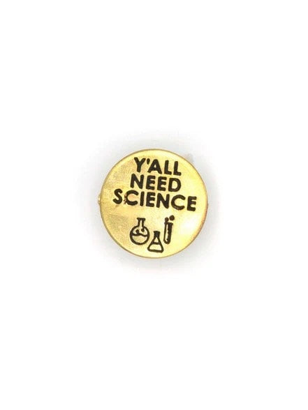 A circular brass pin with "Y'ALL NEED SCIENCE" written in black with black beakers and test tubes.